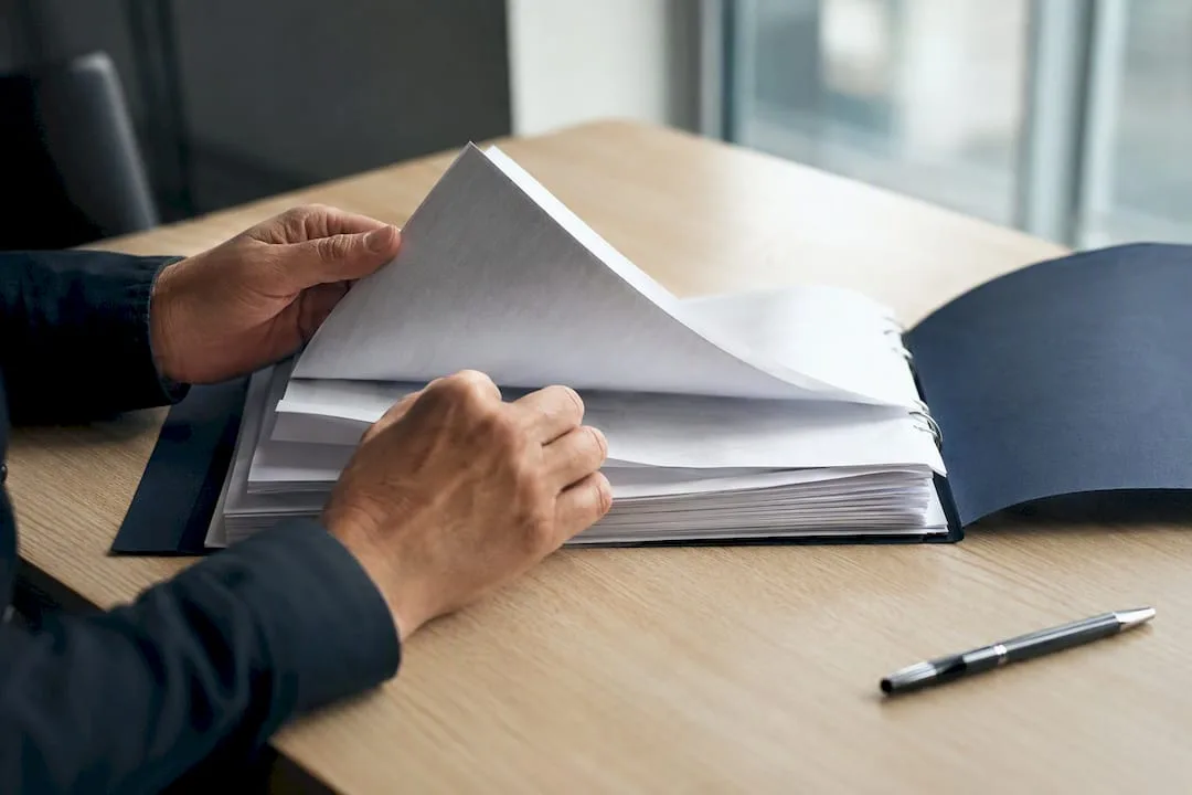 Hands leafing through an audit register